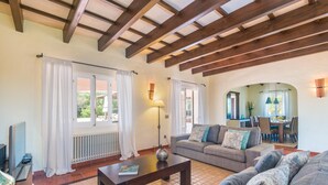 A living room with a sofa, a coffee table, a lamp, and a dining area with chairs and a table. - Villa Mig Coster - A rural retreat on a private estate (Sant Lluís)