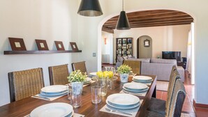 A dining area with a wooden table set for six, surrounded by wicker chairs. - Villa Mig Coster - A rural retreat on a private estate (Sant Lluís)