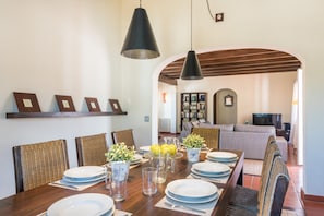 A dining area with a wooden table set for six, surrounded by wicker chairs.