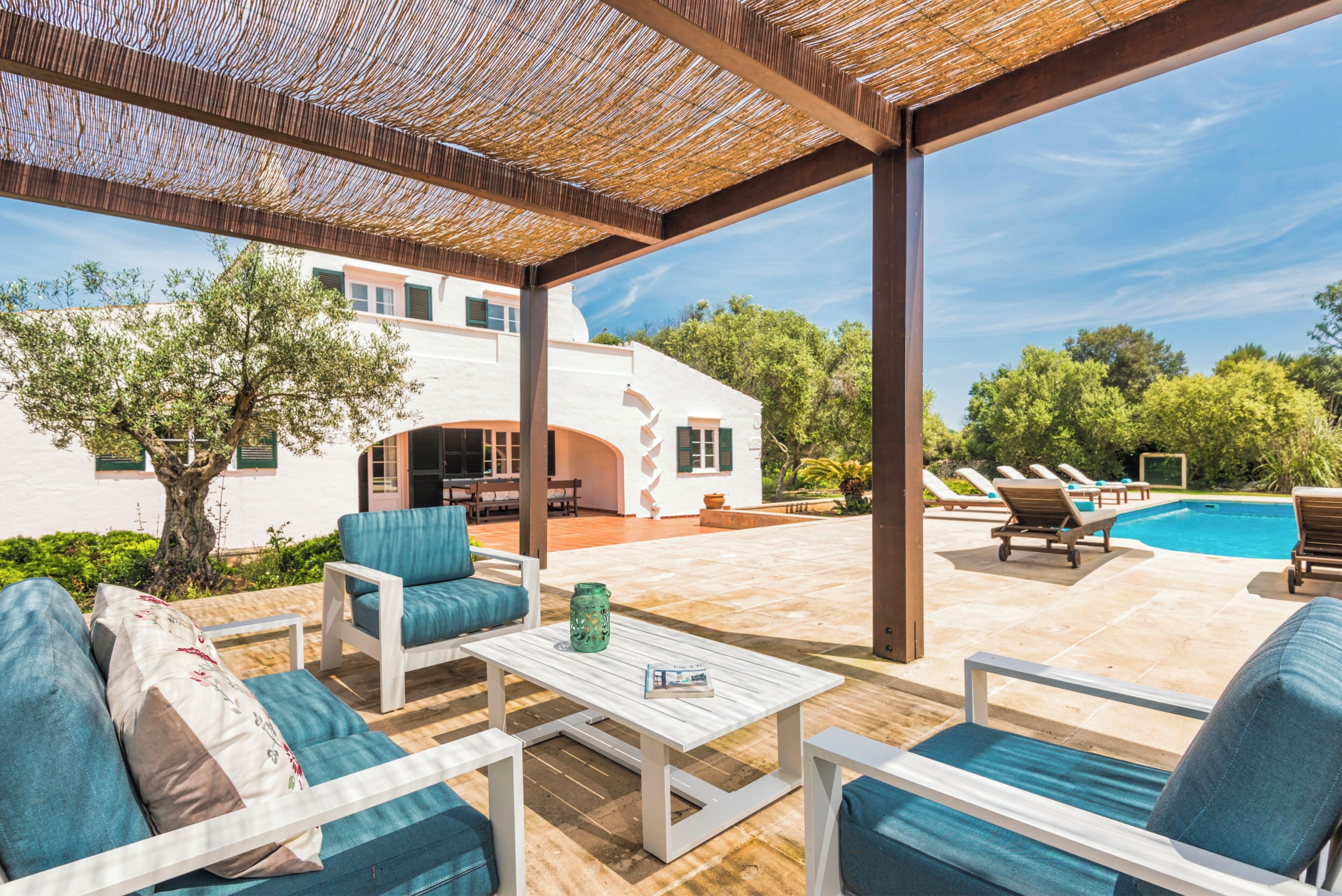 An outdoor patio with a pool, lounge chairs, and a pergola.