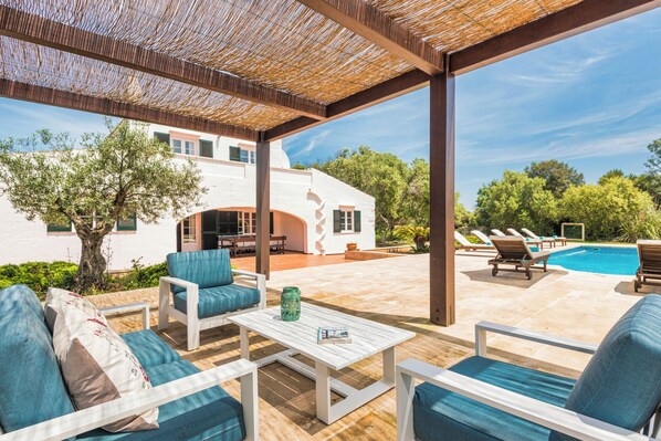 An outdoor patio with a pool, lounge chairs, and a pergola.