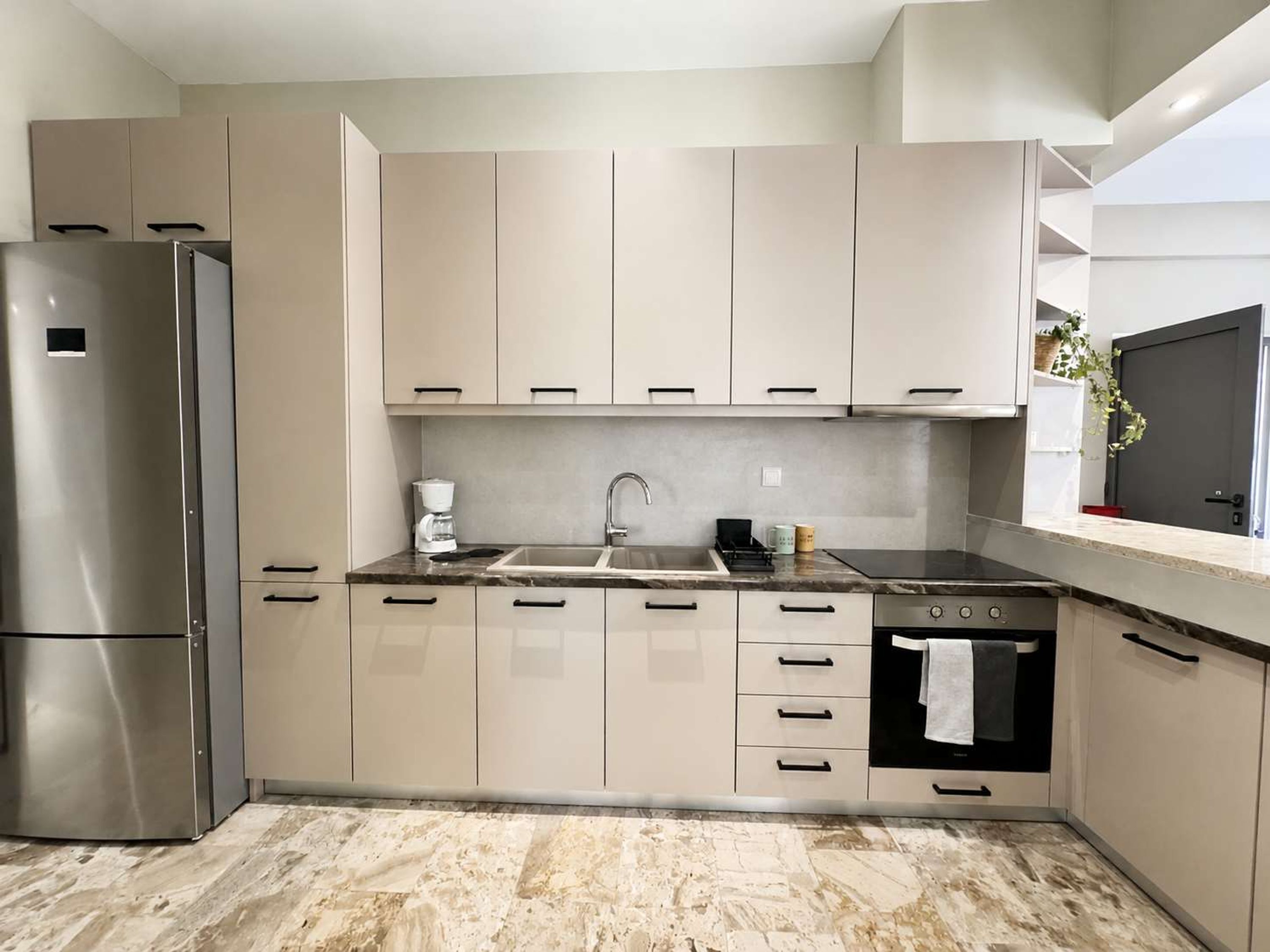Una cocina moderna con un refrigerador de acero inoxidable, un horno empotrado y un lavamanos con grifo.