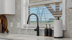 A kitchen with a modern faucet, two soap dispensers, and a window with blinds. - Keystone Lake Getaway (Sand Springs)