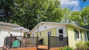 A lodge with a wooden deck, a welcome sign, and a barbecue grill. - Scenic Wine Trail Lodge w/ Decks & Lake Views (Penn Yan)