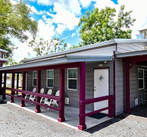 Ein kleines, eingeschossiges Motel mit überdachter Veranda und weißen Plastikstühlen.