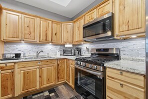 Eine moderne Küche mit Holzausstattung, einer Edelstahl-Mikrowelle, einem Gasherd und einem eingebauten Backofen.