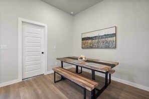 A room with a white door, a painting, a wooden bench, and a table. - The Sage - 3BR/2BA - New Construction (Lubbock)