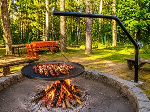 Ein Grill mit Spießen, umgeben von einer Steinkaminanlage.