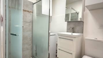 A modern bathroom with a glass shower enclosure, a white sink, and a toilet.