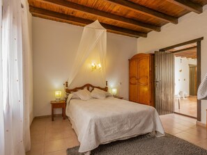 Une chambre à coucher avec un lit à baldaquin, une armoire en bois et une vue sur l’extérieur.