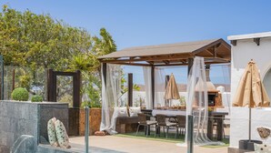 Piscina com pérgola e área de estar ao ar livre.