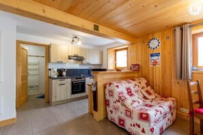 A wooden interior with a kitchenette, a sofa, and a dining area. - LA BARTAVELLE - LA GIETTAZ (LA GIETTAZ)