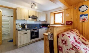 A compact kitchen with wooden cabinets, a built-in oven, a small window, and a clock on the wall. - LA BARTAVELLE - LA GIETTAZ (LA GIETTAZ)