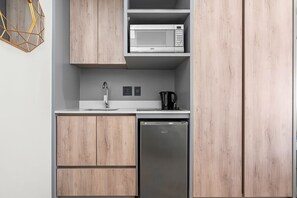 A modern kitchen with wooden cabinets, a built-in microwave, a coffee maker, and a dishwasher. - One Thibault 1609 - Studio Apartment, Sleeps 2 (Cape Town)