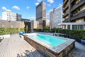 A rooftop pool with a wooden deck, surrounded by city buildings. - One Thibault 1929 - Studio Apartment, Sleeps 2 (Cape Town)