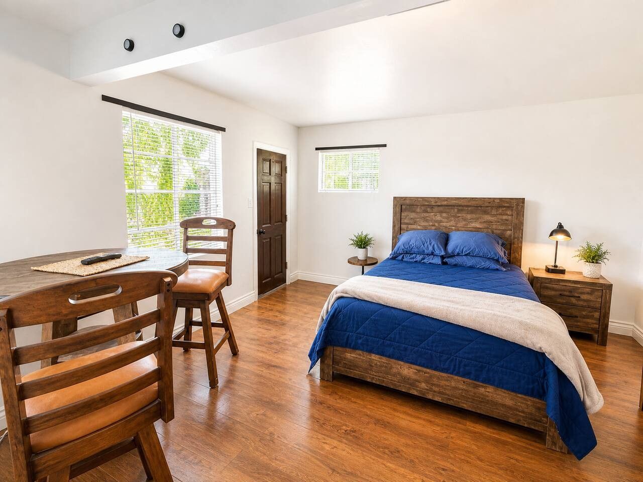 Een slaapkamer met een houten bed, een bureau en stoelen.