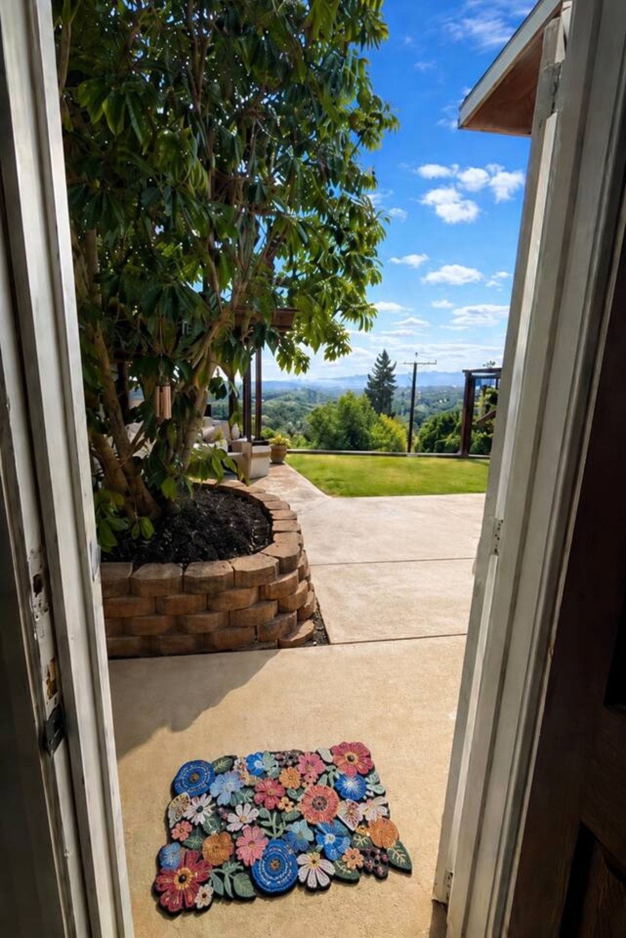 Ein Durchgang zu einer überdachten Terrasse mit einem Ziegelpflanzgefäß und einem bunten Teppich.