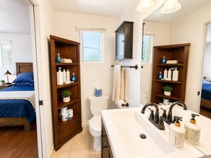 Een badkamer met een witte wastafel, twee spiegels, een toilet en een douche.