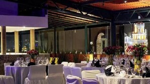 A banquet hall with round tables set for a formal event, featuring white tablecloths and chairs with white coverings. - Best Western San Pedro Puebla (Puebla)