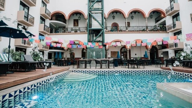 A pool area with a tiled floor, a central staircase, and outdoor seating with umbrellas. - Best Western San Pedro Puebla (Puebla)