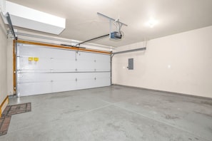 Un garatge amb una porta blanca, un projector fixat al sostre i un sòl de formigó.