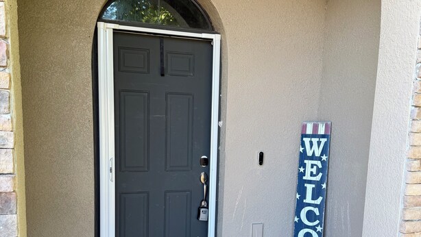 A black door with a keyhole, a welcome sign, and a doormat.