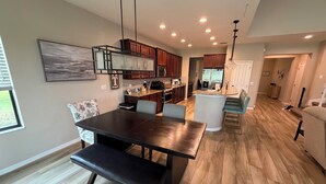 A modern kitchen with wooden cabinets, a central island, and a dining area with a bench.