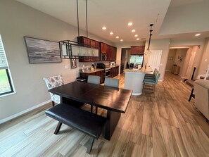 A modern kitchen with wooden cabinets, a central island, and a dining area with a bench.