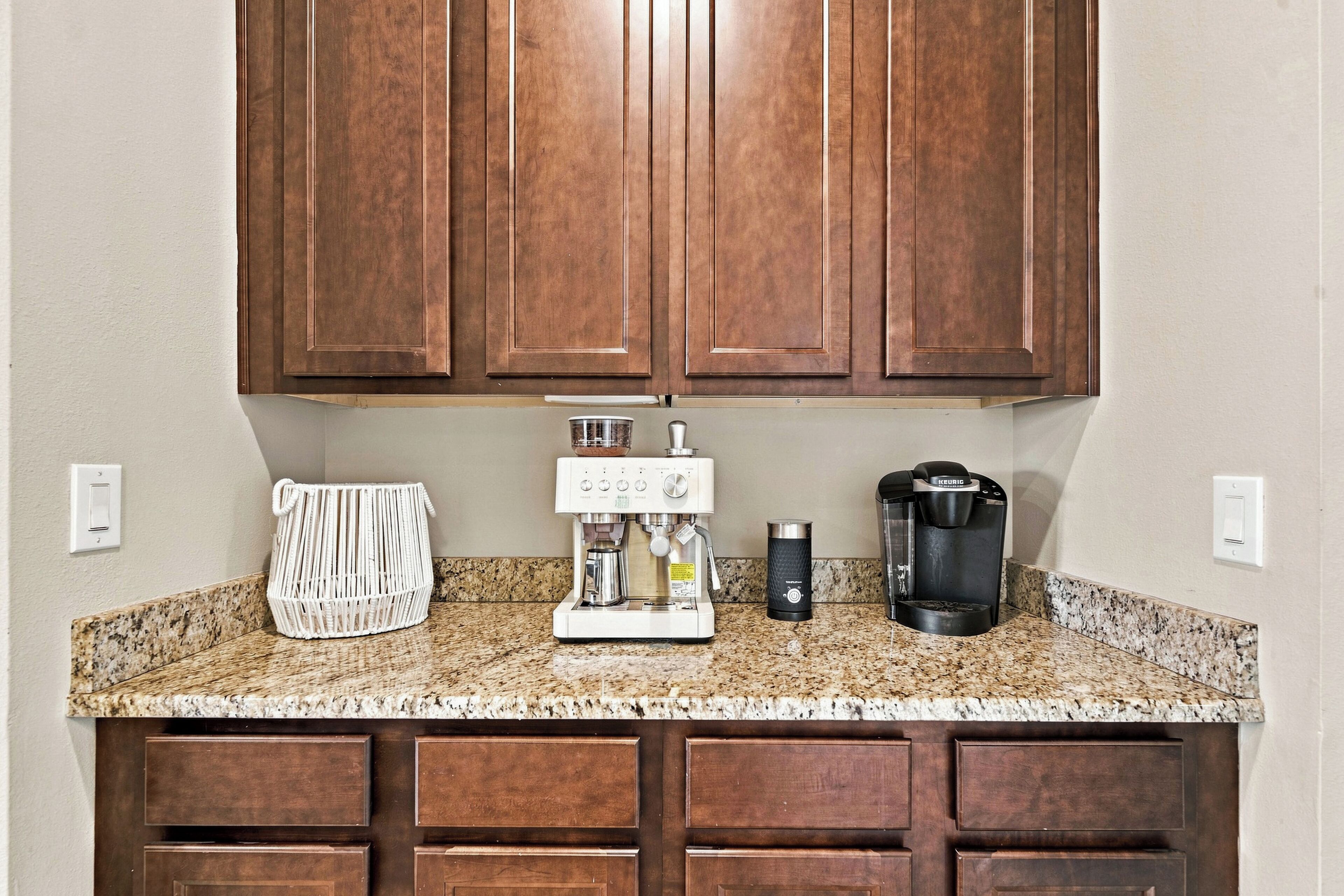 A kitchen with wooden cabinets, a coffee maker, a kettle, and a woven basket on the countertop.