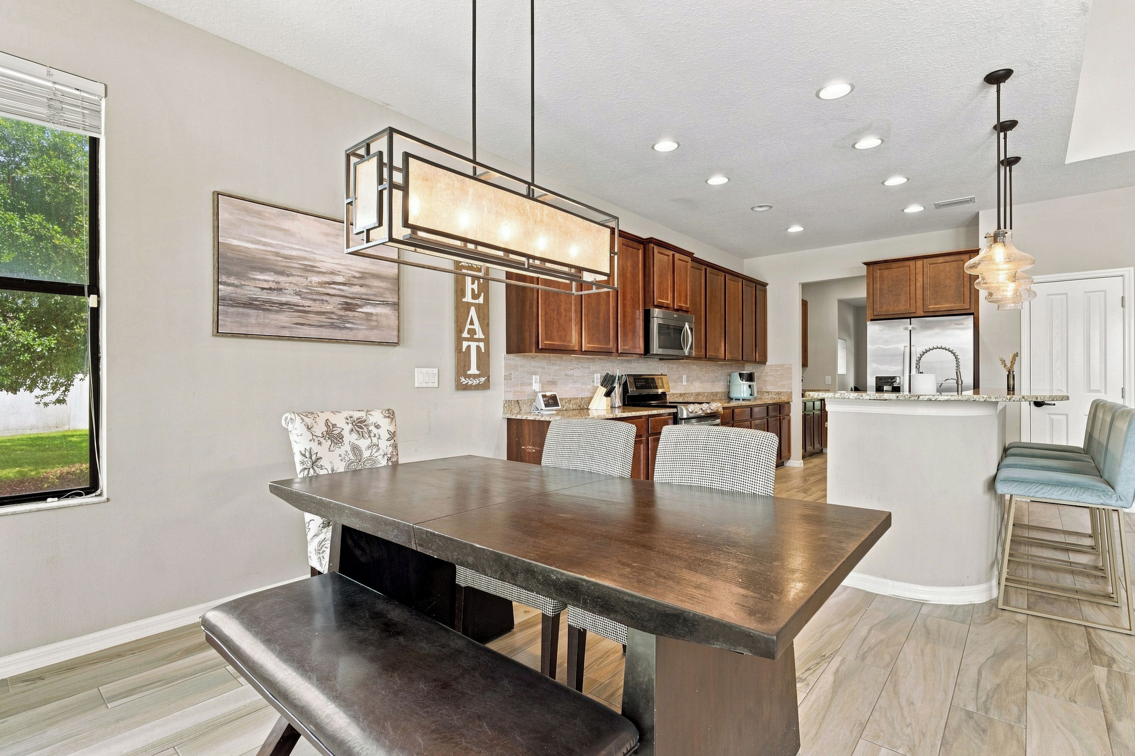 A modern kitchen with a central island, wooden cabinets, and a dining area with a bench.