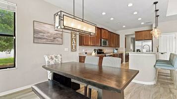 A modern kitchen with a central island, wooden cabinets, and a dining area with a bench.