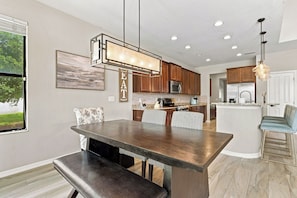 A modern kitchen with a central island, wooden cabinets, and a dining area with a bench.