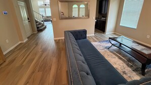 A living room with a sofa, a coffee table, and a dining table. There is a staircase leading to another level.