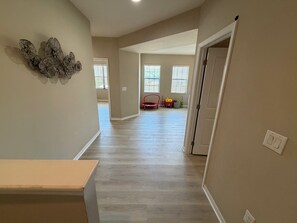 Un pasillo espacioso con piso de madera, una puerta a la derecha y un adorno floral decorativo en la pared.