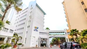 A hotel entrance with a modern design, a parking area, and a vehicle parked outside. - Sunlit Studio ° Private Balcony & Lagoon Views (San Juan)