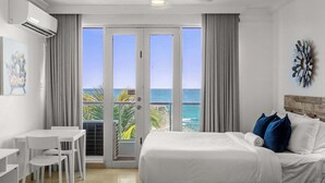 Een hotelkamer met een bed, een bureau, stoelen en uitzicht op de oceaan.