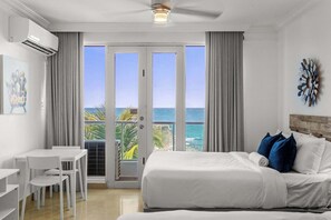 Ein Hotelzimmer mit Bett, Schreibtisch, Stühlen und Blick aufs Meer.
