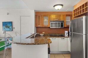 Eine Küche mit Granit-Arbeitsplatten, Edelstahlgeräten, Holzschränken und einer gläsernen Kochinsel.