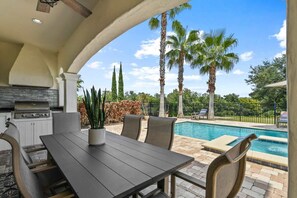 An outdoor patio with a pool, seating, and a grill area. - 5BR family villa w/ pool & hot tub (Kissimmee)