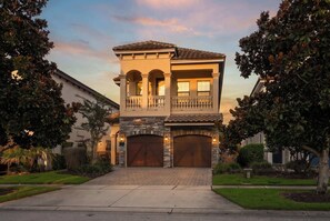 A two-story house with a stone facade, a balcony, and a garage. - 5BR family villa w/ pool & hot tub (Kissimmee)
