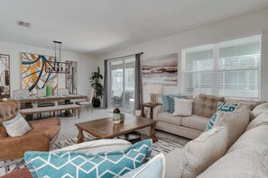 Ein Wohnzimmer mit Sofa, Couchtisch und Essbereich mit Stühlen und Tisch.