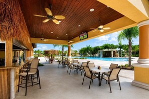 Eine Terrasse im Freien mit Sitzgelegenheit, Pool und Fernseher.