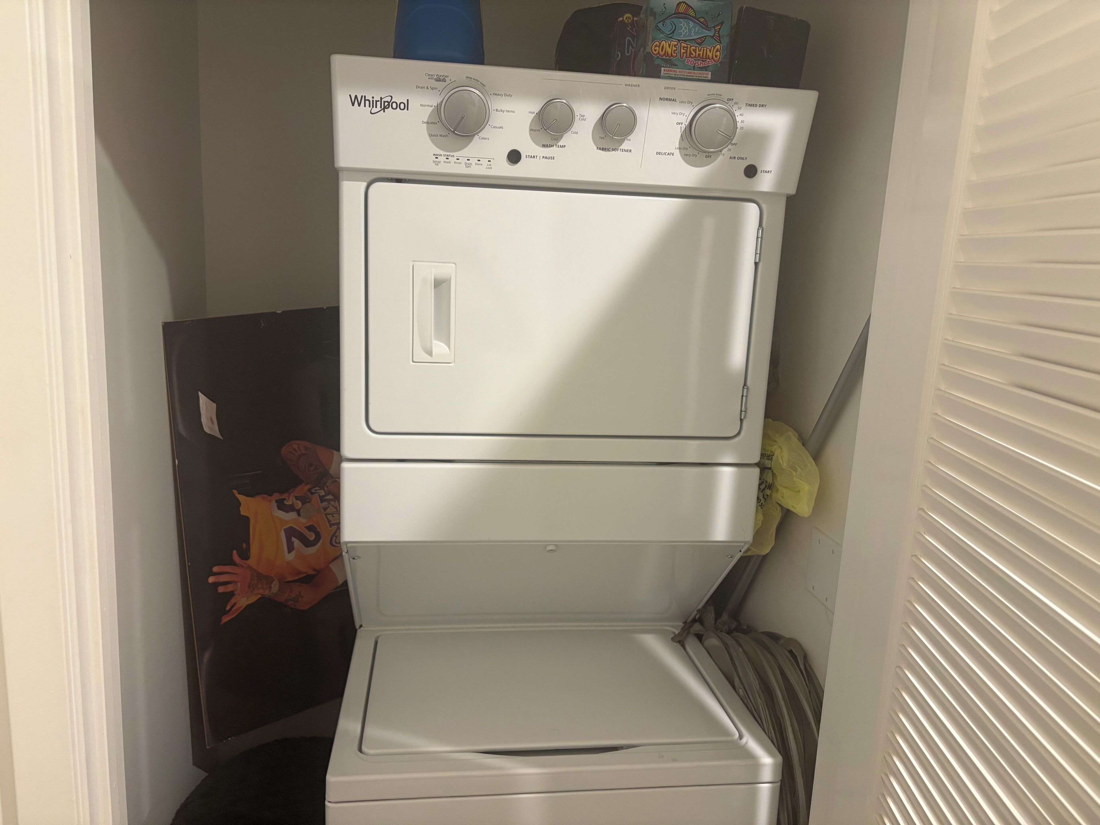 Eine kompakte Waschmaschine und ein Trockner mit Bedienknöpfen und einem Startknopf, platziert in einem kleinen Waschraum.