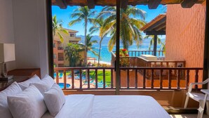 Habitación de hotel con balcón, cama y vista a la playa y al océano.