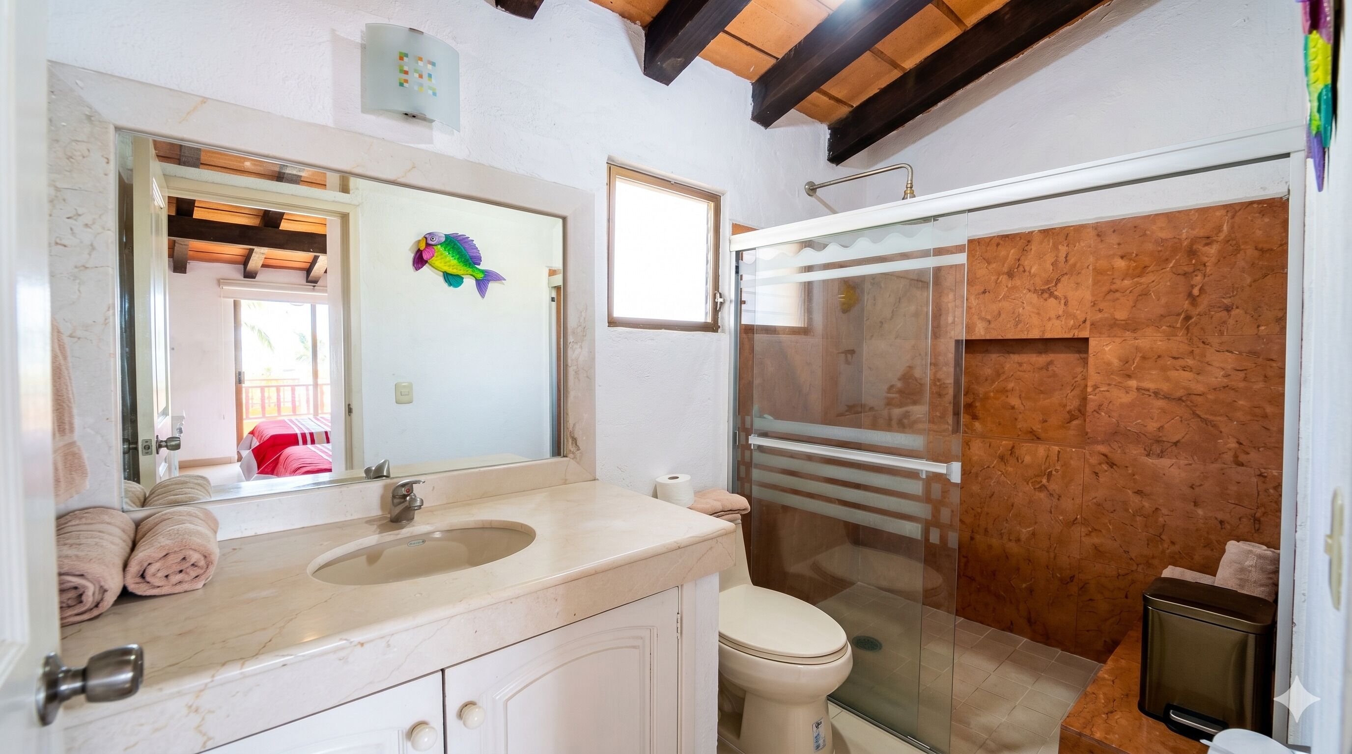 A bathroom with a sink, mirror, toilet, and shower.