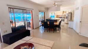 Un espacio moderno para vivir con mesa y sillas de comedor, sofá y cocina con armarios y electrodomésticos blancos.