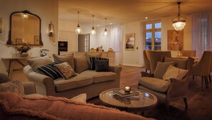 A living room with a sofa, armchairs, a coffee table, and a dining area with a table and chairs. - Your Villa Réthaise for 10 People with Heated Indoor Pool (Sainte-Marie-de-Ré)