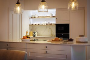 A modern kitchen with white cabinetry, a marble countertop, and a central island with various items. - Your Villa Réthaise for 10 People with Heated Indoor Pool (Sainte-Marie-de-Ré)