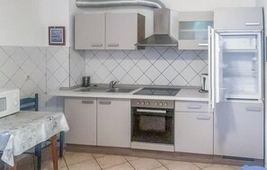 Eine Küche mit Mikrowelle, Spüle, Herd, Backofen und Kühlschrank.