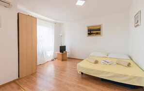Ein Schlafzimmer mit Bett, Fernseher, einem Gemälde und einem Fenster mit Vorhang.